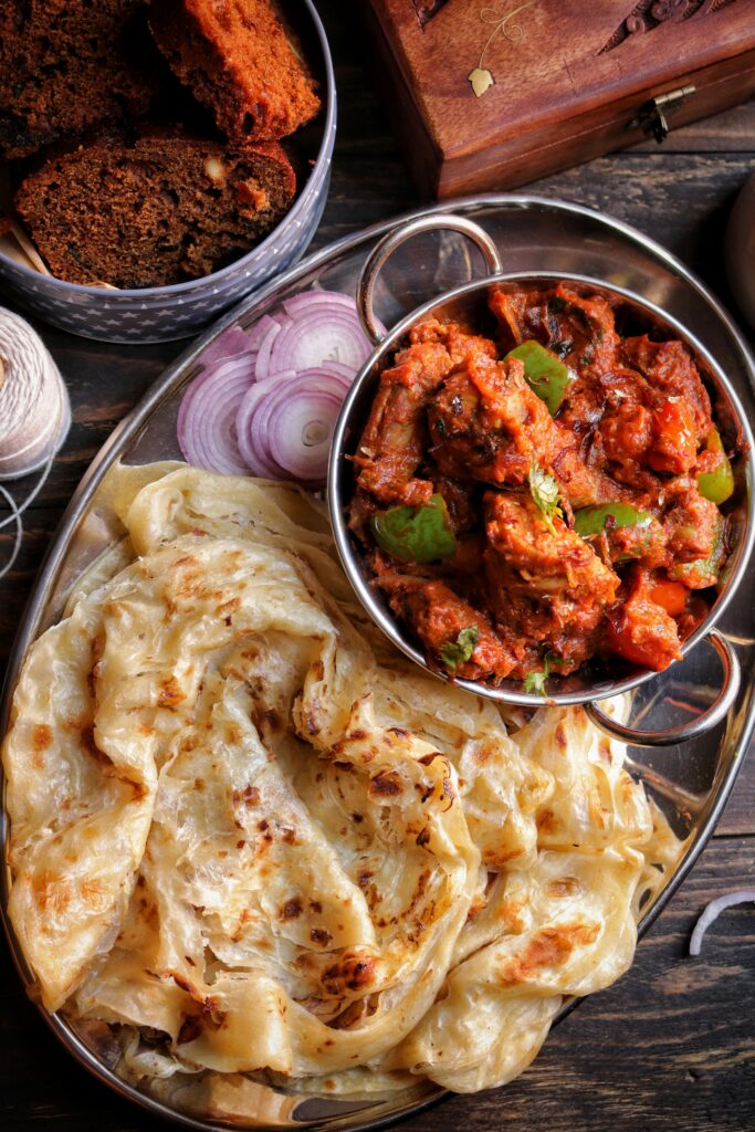 Close-up of Indian cuisine featuring paratha and spicy curry served with sliced onions.